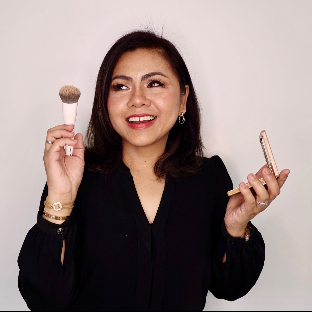 Joyce Valencia smiling, holding a makeup brush and a compact