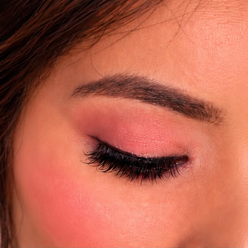 A pink shimmer lid, eyes closed, lashes curled
